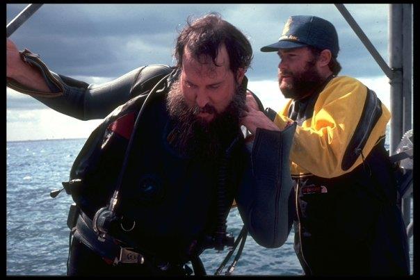 Spence in yellow drysuit assists boat captain Steve Howard with his dive gear.