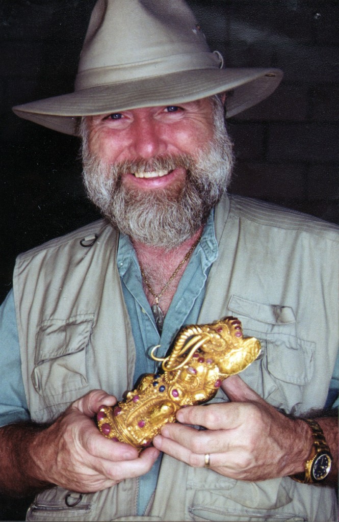 A smiling, tanned and bearded, Dr. E. Lee Spence displays a ruby & sapphire studded, gold sword handle.
