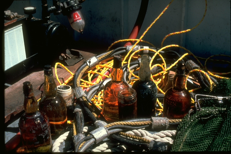 Bottles of Dewar's Scotch salvaged from the Regina, shown sitting among surface supplied diver air hose 