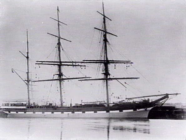 Photo of a three masted barque with a clipper bow at dock