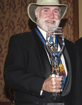 picture of Dr. Spence holding his Nogi Award which is the figure of a skin-diver holding up a plaque with the year of the award